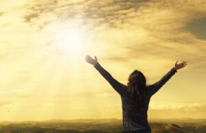 Women with open arms of joy watching the sun