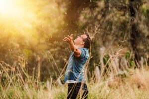 Man on his knees on the grass worshipping God with his arms open